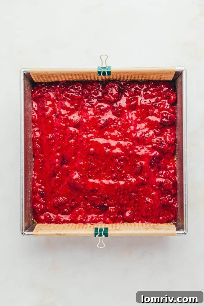 A baking tray with the crust and raspberry filling.