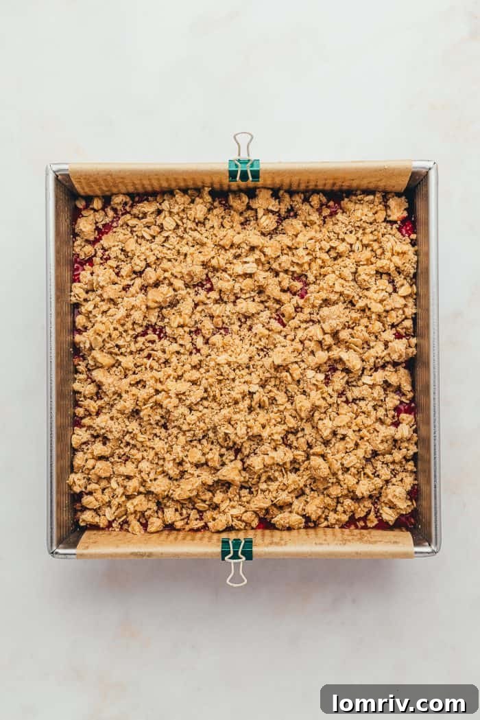 A baking tray with unbaked raspberry crumble bars.