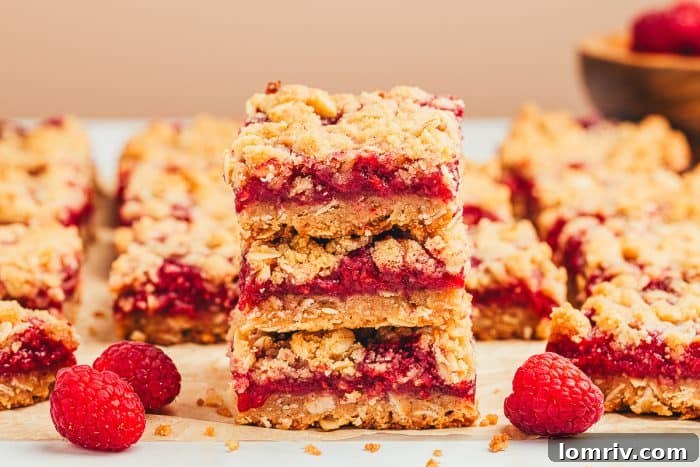 A stack of three raspberry crumble bars with more bars behind it.