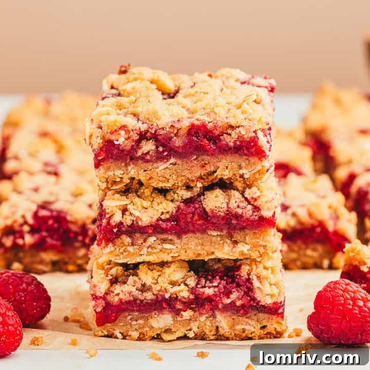 A stack of three raspberry crumble bars with more bars behind it.