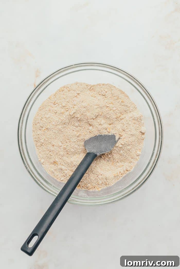 A glass bowl with the dry ingredients for the crumble topping.