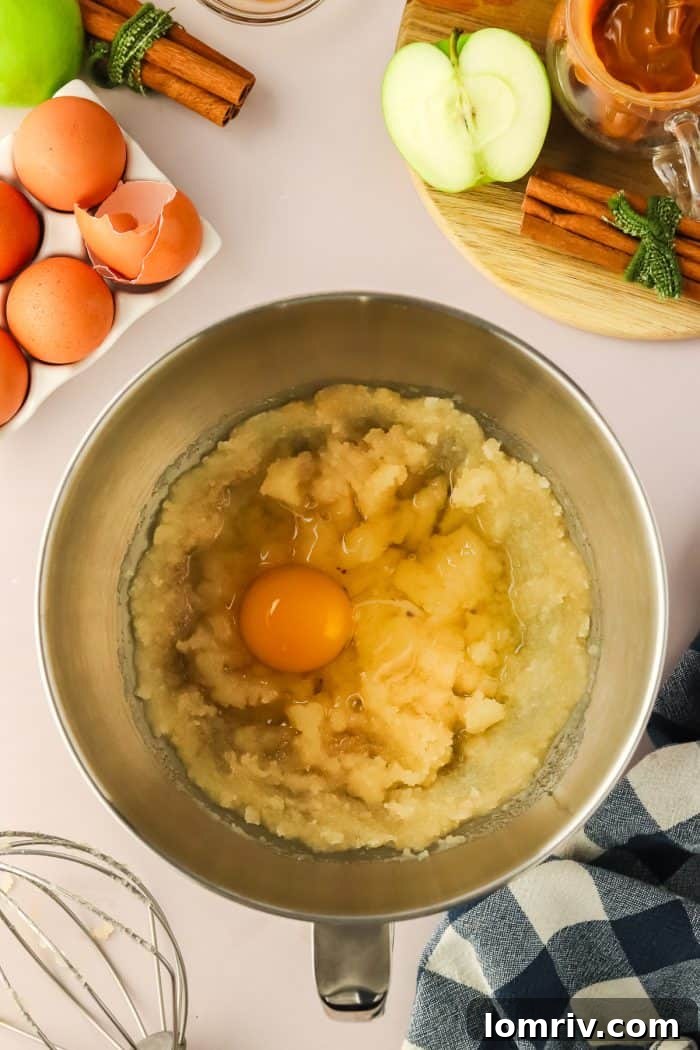 A single large egg is gently folded into the smooth cake batter within a metal mixing bowl, signifying a crucial step in preparing the cake.