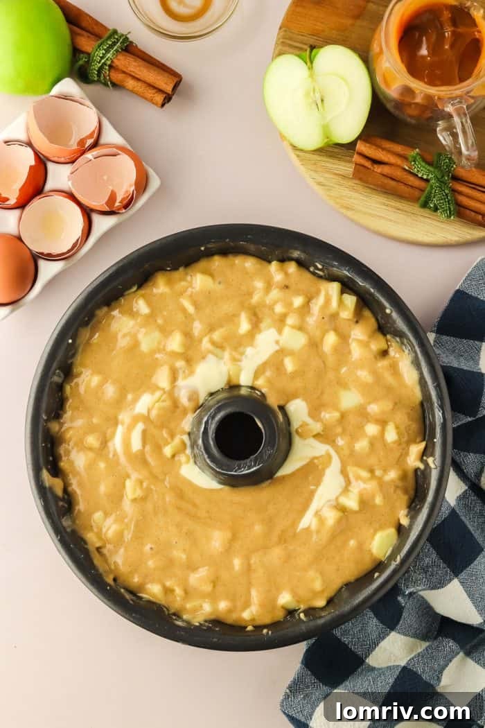 The Bundt pan is now completely filled with the remaining cake batter, smoothly covering the cream cheese layer, ready for baking.