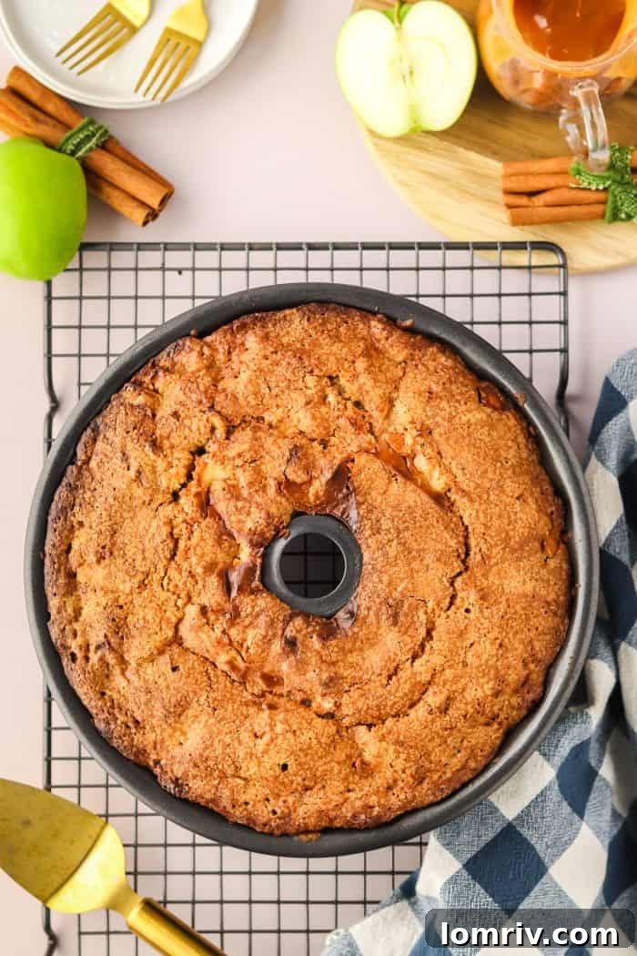 A perfectly baked Caramel Apple Bundt Cake cools gracefully within its ornate Bundt pan on a wire rack, waiting to be inverted and adorned with caramel.