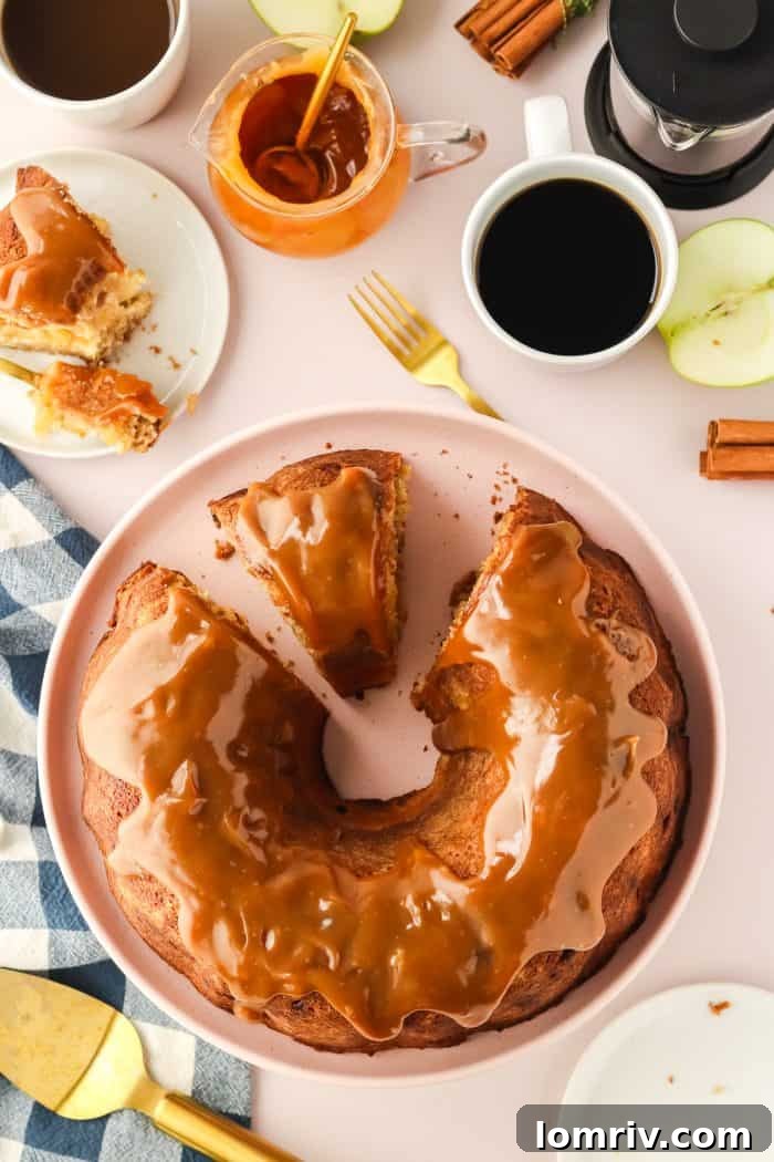 A beautifully sliced Caramel Apple Bundt Cake, revealing its moist interior and creamy cheesecake swirl, with golden caramel sauce glistening on top, ready to be served.