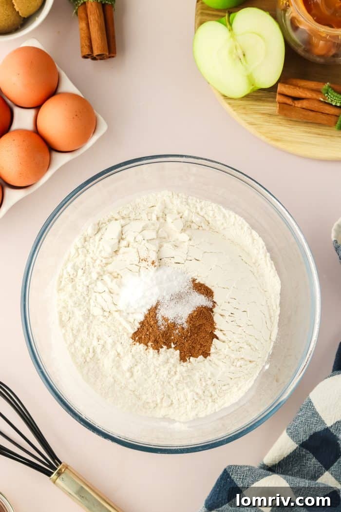 A pristine glass mixing bowl holds a perfectly blended mixture of flour and fragrant cinnamon, ready for the next step in making the apple Bundt cake.