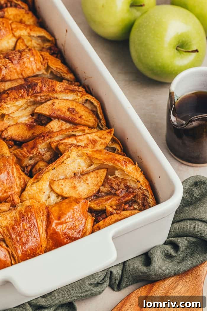 A white dish with baked croissant french toast with apples.