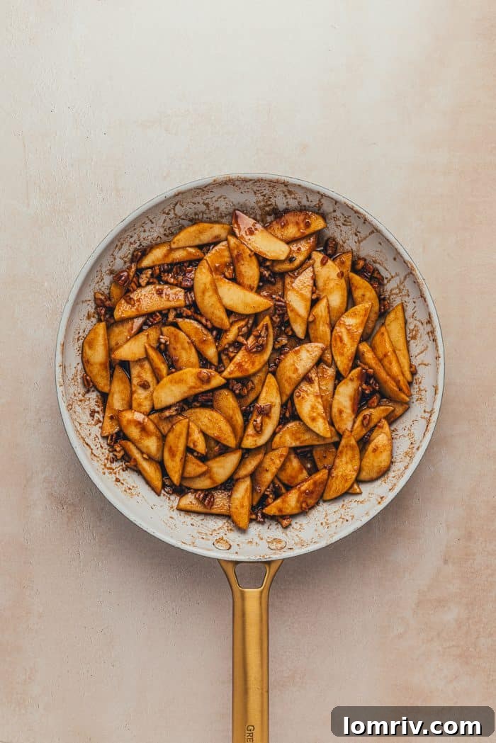 Cooked sliced green apples in a skillet.