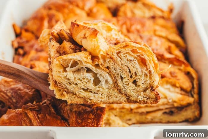A slice of apple french toast bake being removed from a white baking dish.