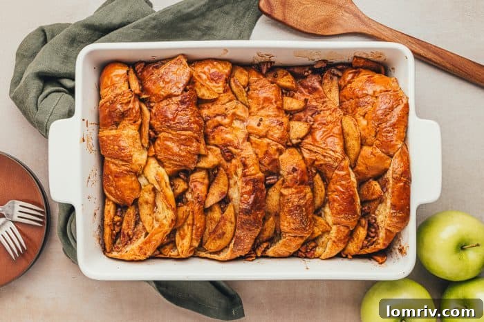 A white dish with baked croissant french toast with apples.