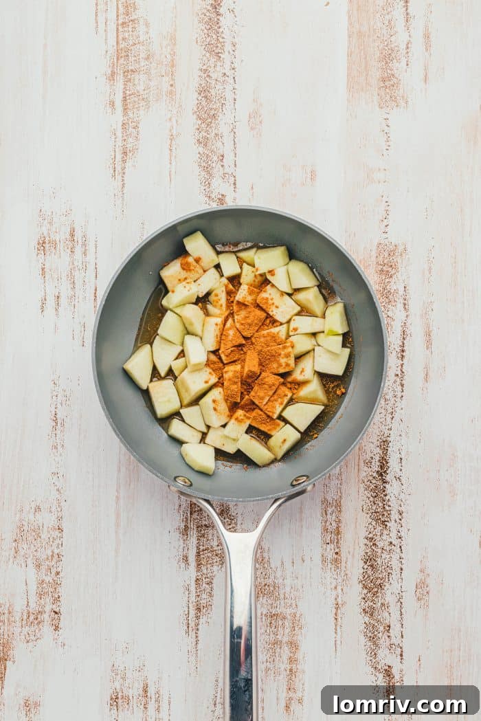 Cubed green apples in a saute pan with cinnamon.