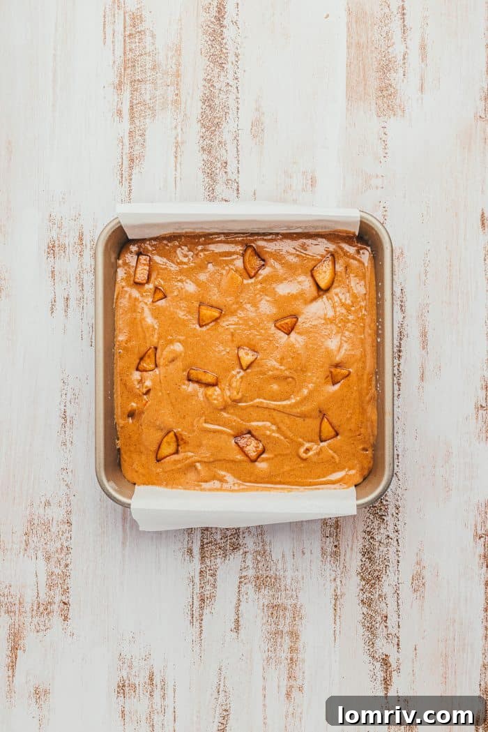 A square baking pan with raw apple Blondie batter.