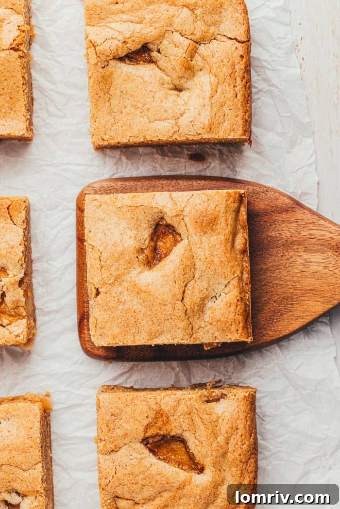 Six Apple Blondies and one is being lifted by a wooden spatula.