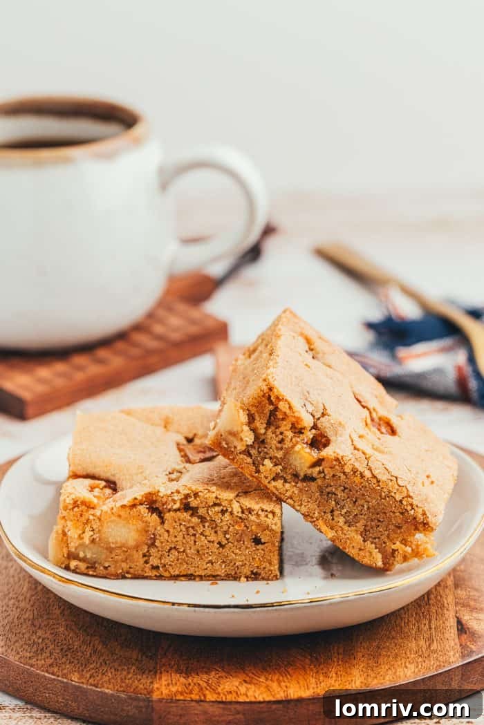A white plate with two Apple Blondies and a cup of coffee in the background.