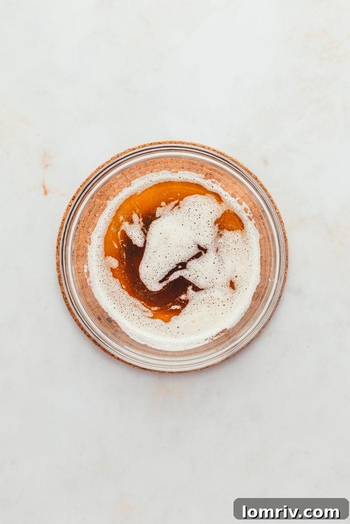 A glass of beautifully browned butter, ready to be cooled and used in the recipe.