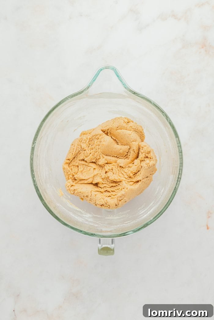 Raw browned butter sugar cookie dough in a glass bowl, showcasing its rich texture.