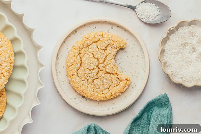 A white plate with a brown butter cookie that has a bite taken out, revealing its soft interior.