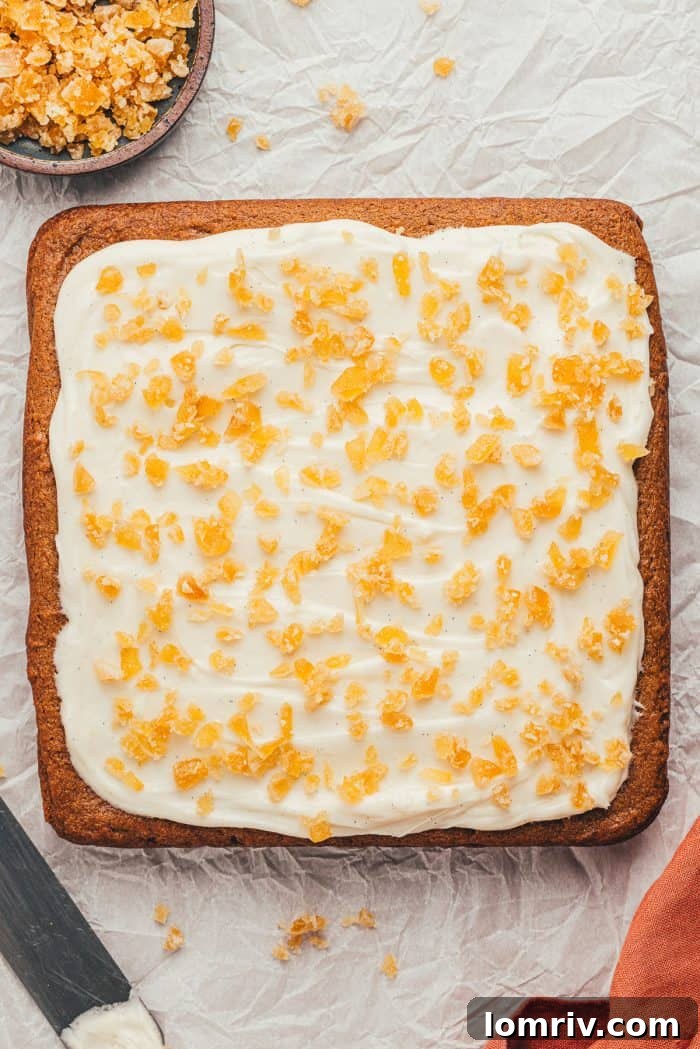 The finished gingerbread bars with a generous layer of cream cheese frosting and a sprinkling of candied ginger on top.