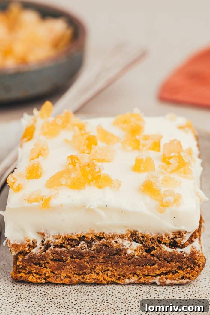Close-up shot of a single frosted gingerbread bar, showcasing its soft texture and the thick layer of cream cheese frosting.