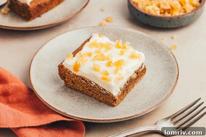A single frosted gingerbread bar on a gray plate, with a fork, suggesting it's time to enjoy this delightful treat.