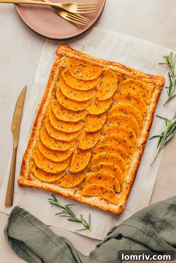 A beautifully plated butternut squash tart with a golden knife nearby, ready to be served.