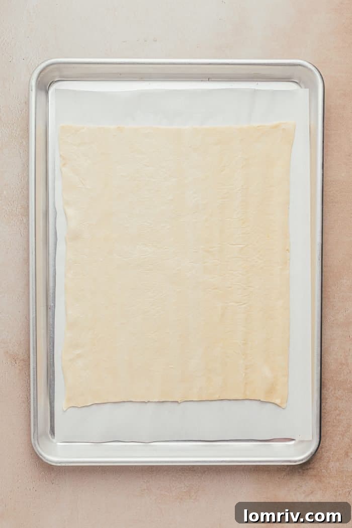 A pristine sheet of puff pastry smoothly rolled out on a baking sheet, ready for the next step.