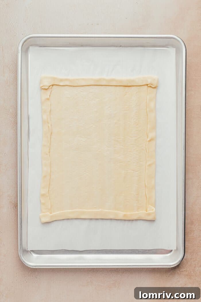 Puff pastry rolled out on a baking sheet, with its edges neatly folded in to form a defined crust.