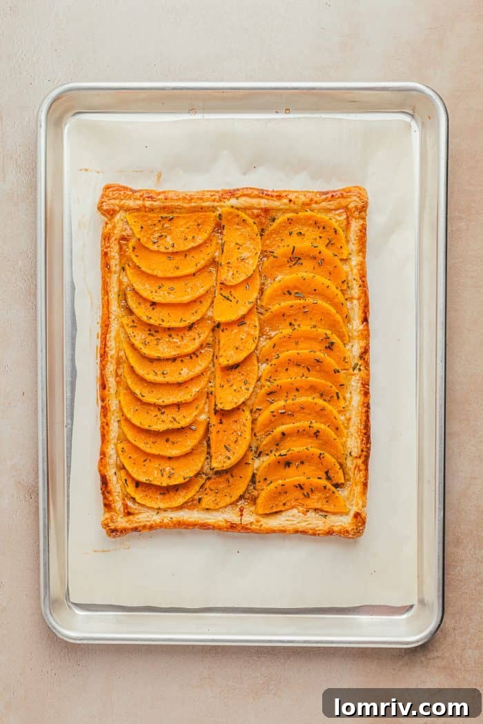 A perfectly baked butternut squash tart, golden brown and puffed, cooling on a baking sheet.