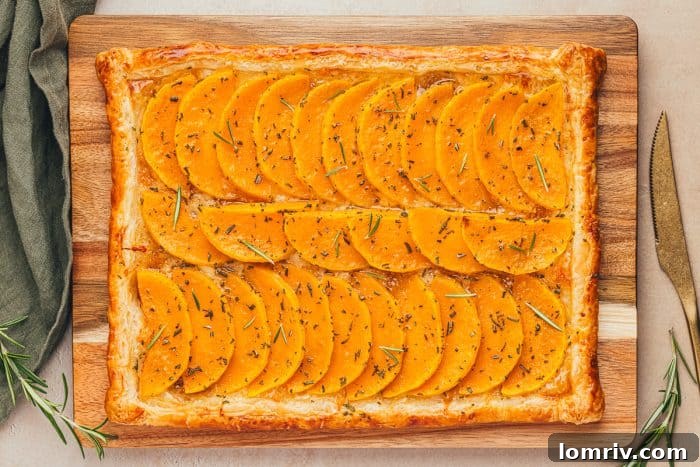 An entire easy butternut squash tart beautifully displayed on a wooden cutting board, ready to be sliced and served.