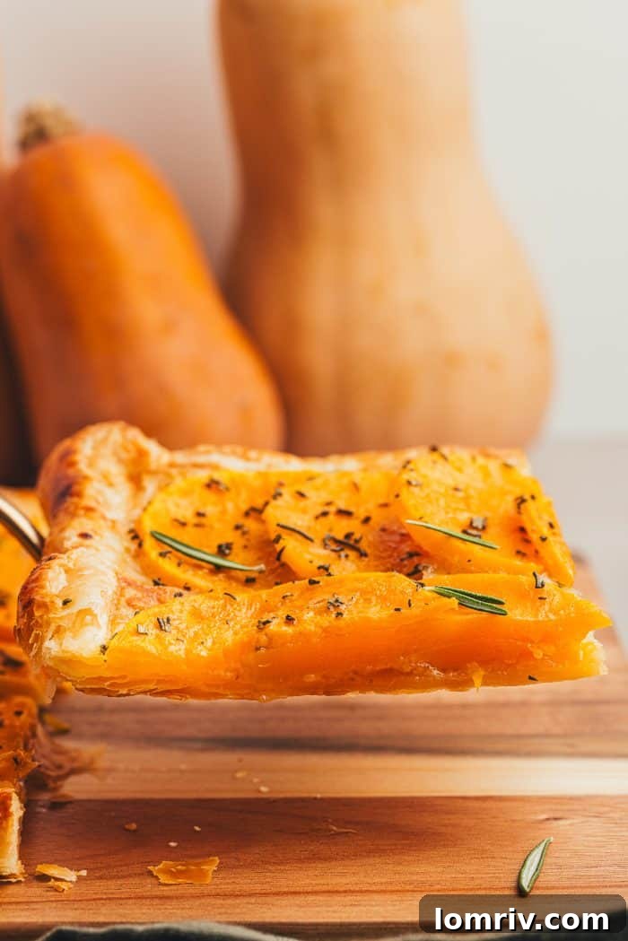 A delectable slice of butternut tart artfully presented, with two whole butternut squashes blurred in the background, hinting at fresh ingredients.