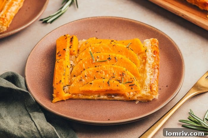 A close-up shot of a single slice of butternut squash tart on a brown plate with a gold fork, ready to be enjoyed.