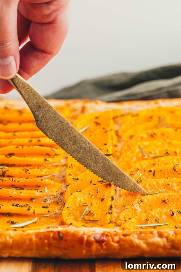 A golden knife gracefully cutting through a freshly baked butternut squash tart, revealing its tender layers.