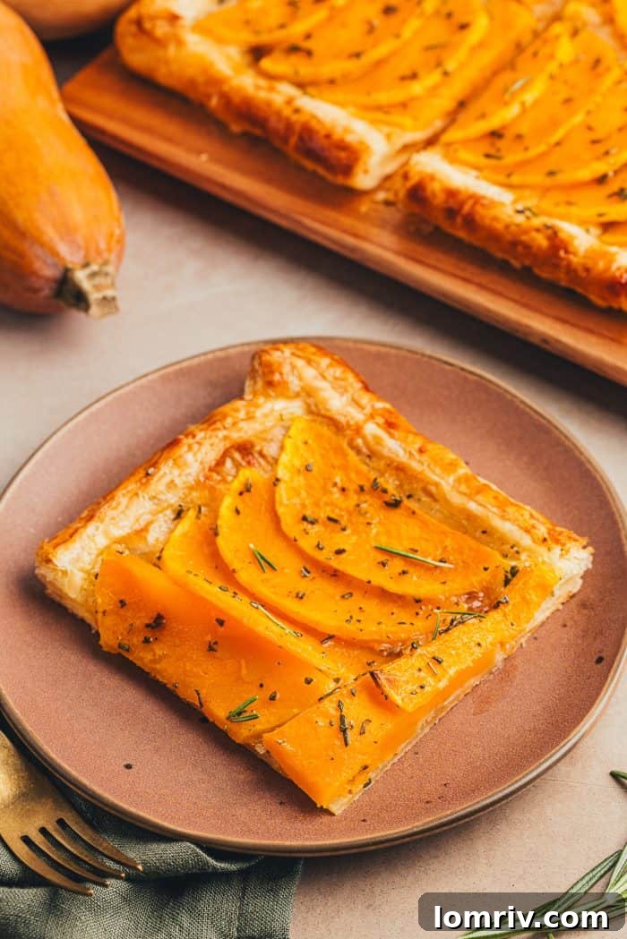A single, delectable slice of butternut squash tart elegantly presented on a brown plate with a gold fork.
