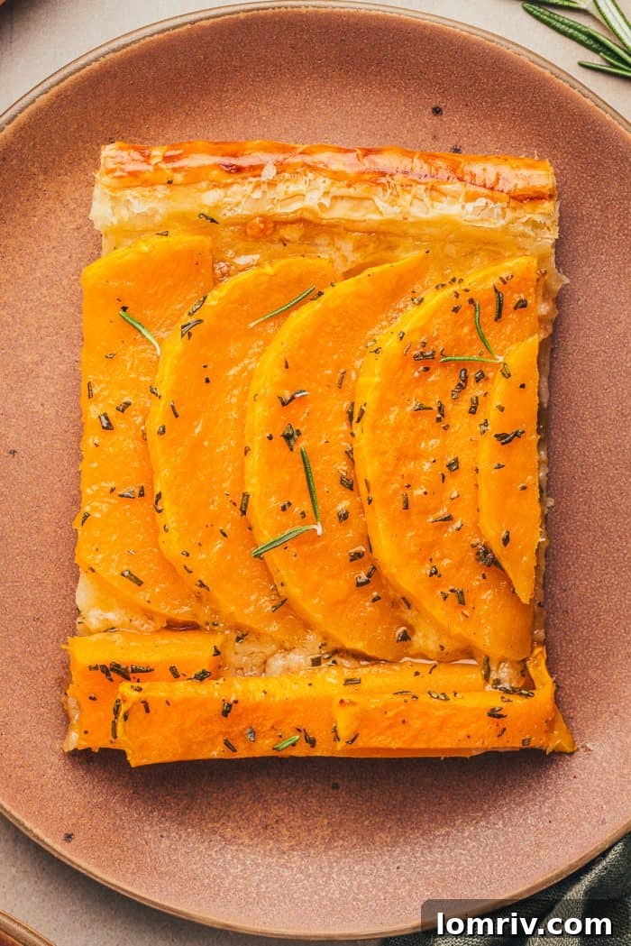 A close-up shot of a single slice of butternut squash tart, highlighting its perfectly golden crust and tender filling.