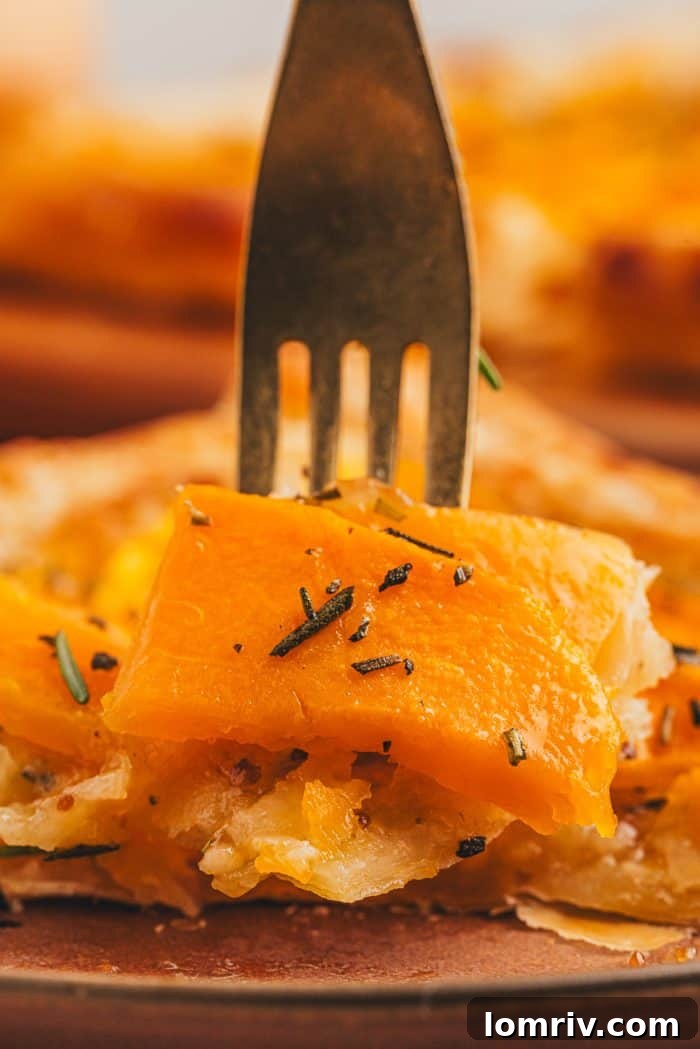 A fork piercing through a succulent slice of butternut squash tart, ready for a taste.