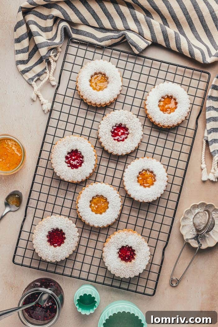 A cooling rack with beautifully arranged Spiced Hazelnut Linzer cookies and a festive tea towel.