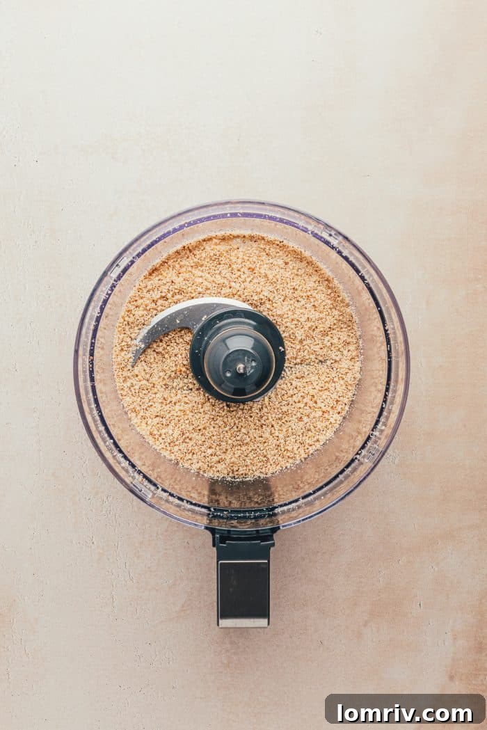 A food processor containing whole hazelnuts, finely ground and ready to be incorporated into the cookie dough.