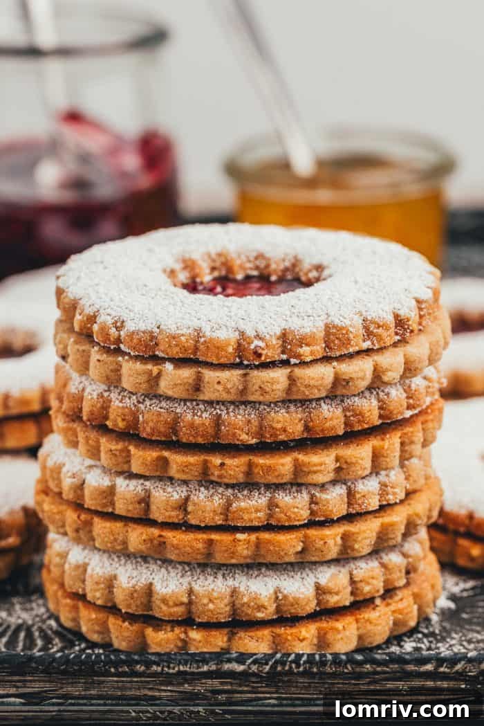 A perfectly stacked tower of Spiced Hazelnut Linzer cookies, showcasing their intricate design and jam filling.