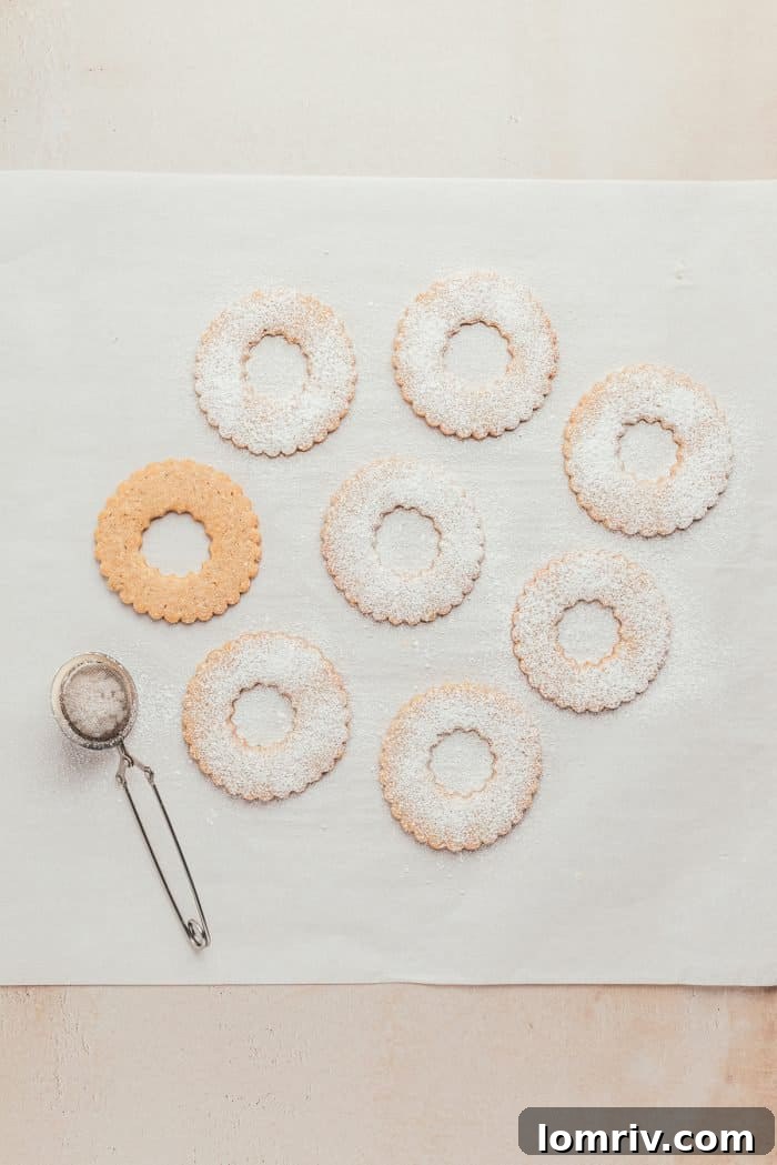 The top halves of baked Linzer cookies, elegantly dusted with powdered sugar, creating a snowy, festive appearance.