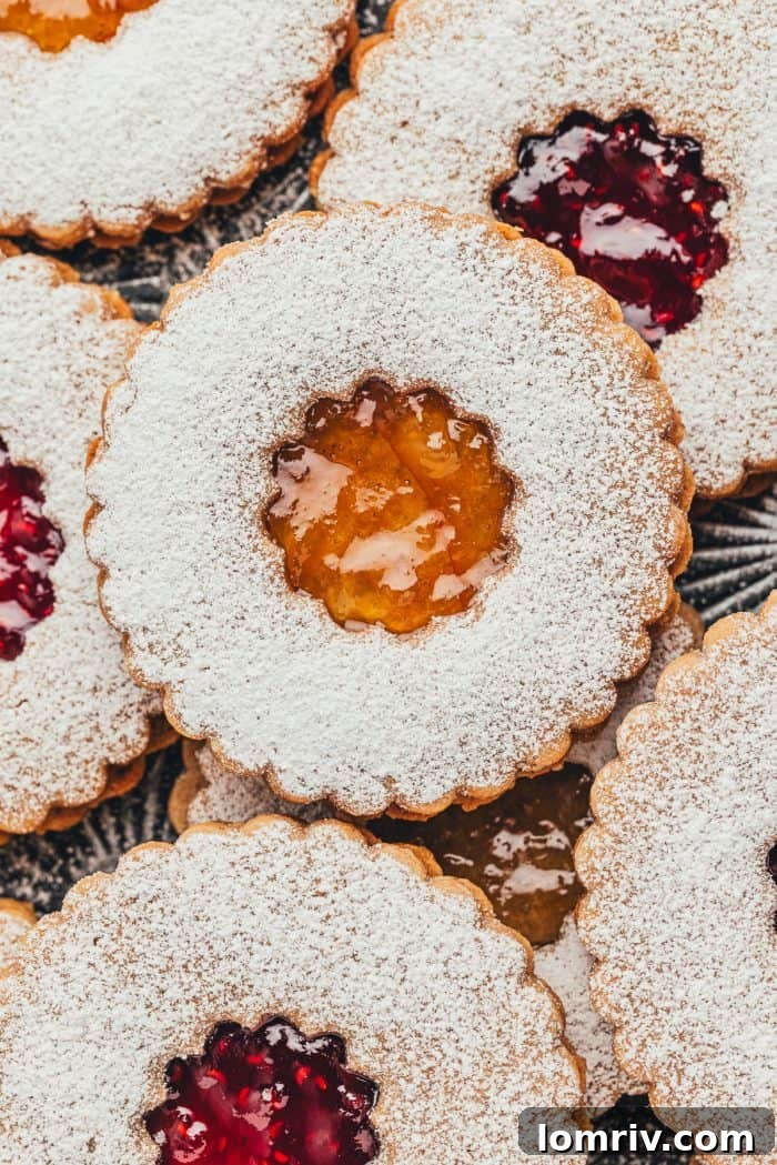 An inviting close-up of finished Linzer cookies, showcasing the glistening jam centers peeking through the dusted cookie tops.