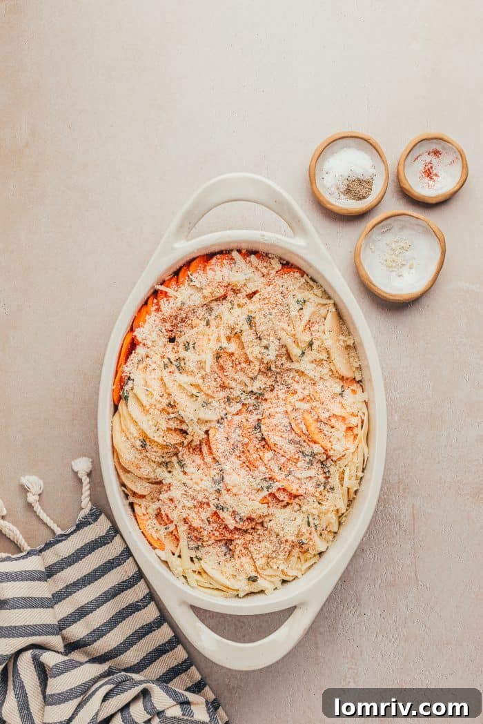 Root vegetables in a baking dish sprinkled with paprika, parmesan, salt, and pepper.