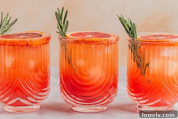 A final photo of three elegantly presented blood orange mocktails, ready to be enjoyed, showcasing their vibrant color and garnishes.