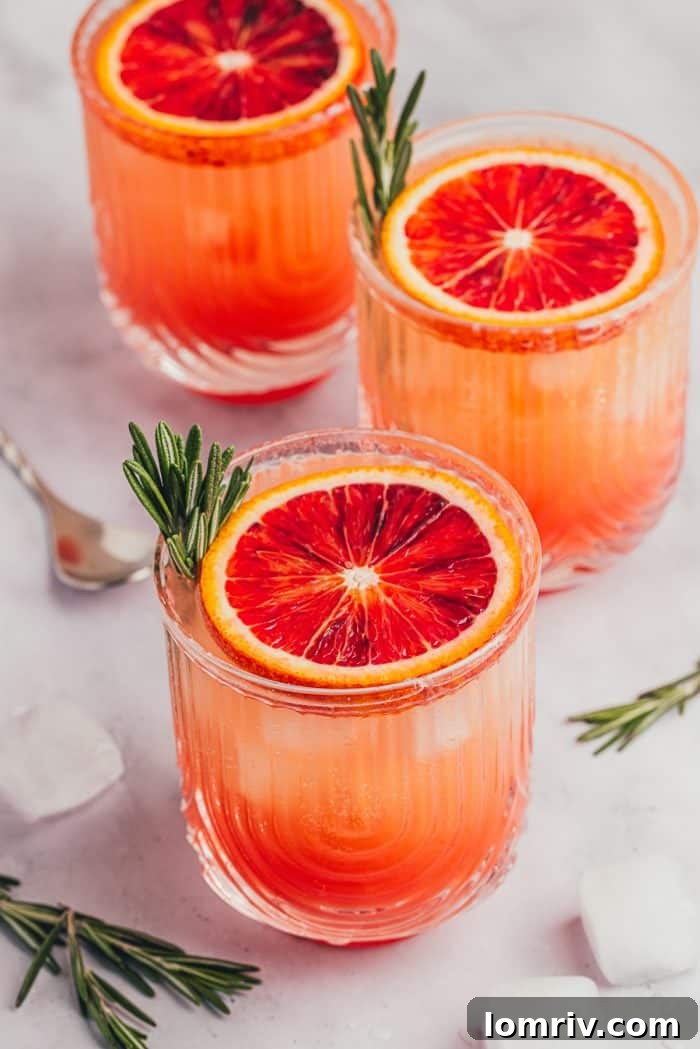 Three beautifully prepared blood orange mocktails, each garnished with fresh rosemary and a blood orange slice, ready to be served.