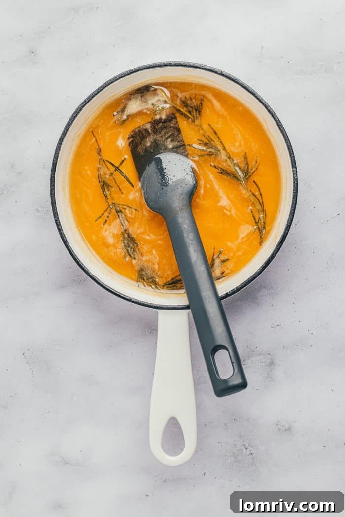 The rosemary honey syrup simmering gently in a saucepan, the rosemary sprigs visibly infusing their flavor.