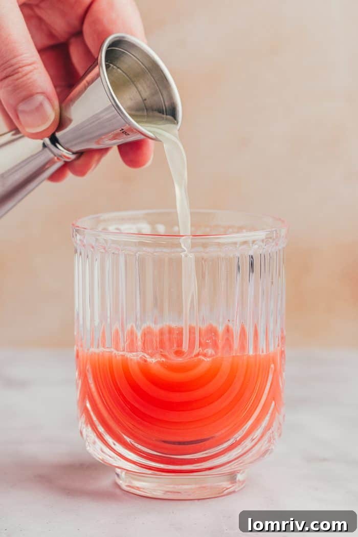 Fresh lime juice being squeezed into the glass with blood orange juice.