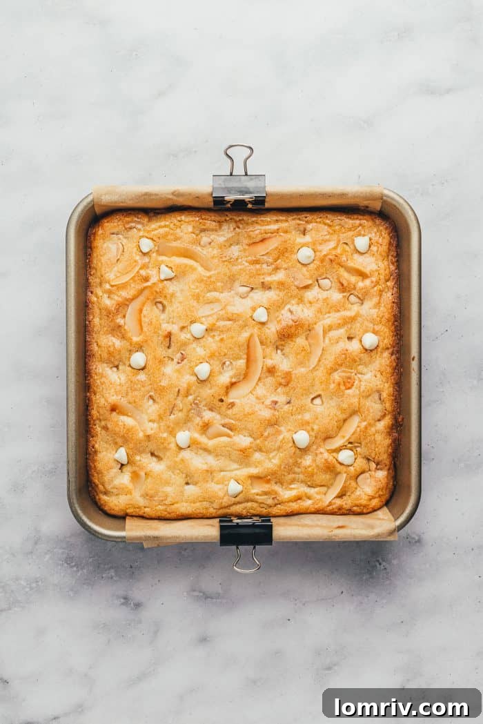 A baking tray filled with golden-brown, freshly baked lemon blondies, showing their perfectly crisp edges.