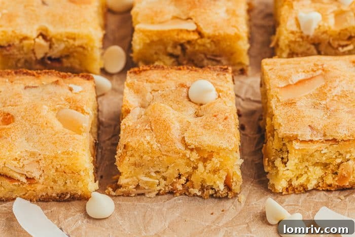Two neat rows of lemon blondies, garnished with a sprinkle of white chocolate chips, on a textured surface.