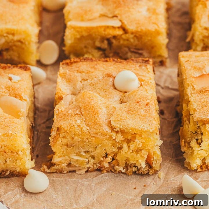 Lemon blondies in two rows with white chocolate chips scattered around them.