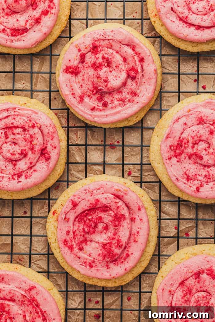 A beautifully arranged platter of lemon sugar cookies, each topped with raspberry cream cheese frosting and a sprinkle of crushed raspberries.