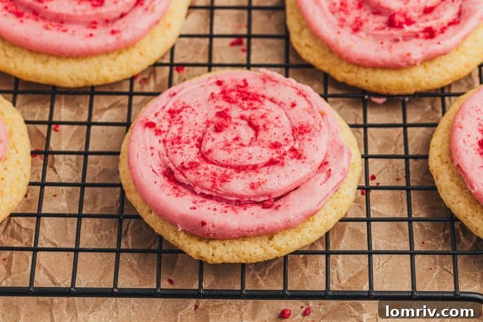 A stunning close-up of lemon sugar cookies with raspberry cream cheese frosting, garnished with fresh raspberries.